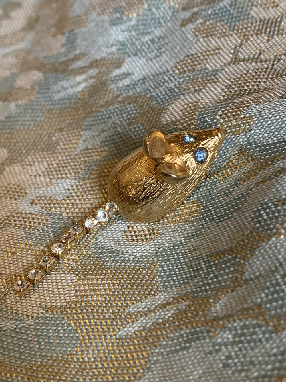 Small gold mouse pendant on fabric